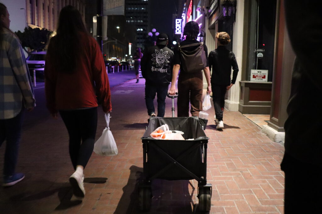 A group of volunteers with Streets of Hope pull a wagon through Gaslamp Quarter full of supplies to give out to the homeless community.